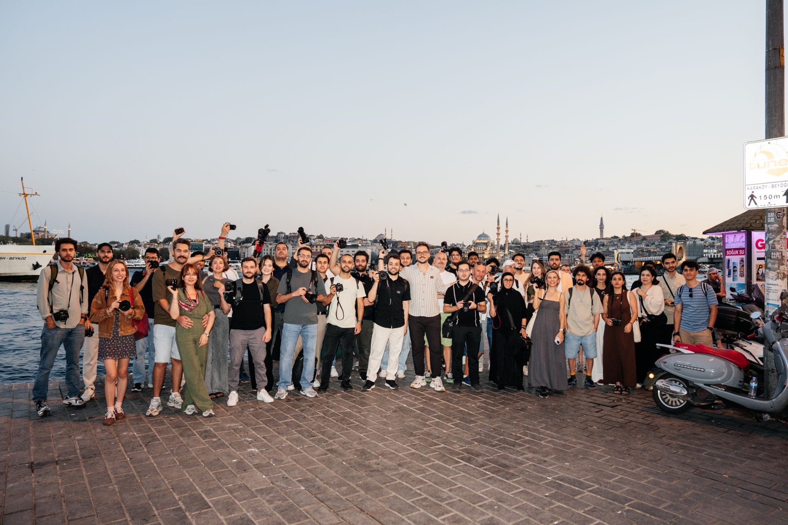 A Pexels photowalk on the Galata waterfront in Istanbul, dozens of photographers holding up their cameras at dusk.